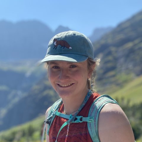 Mac Millard smiling on a mountain hike, wearing a cap with a fox on it